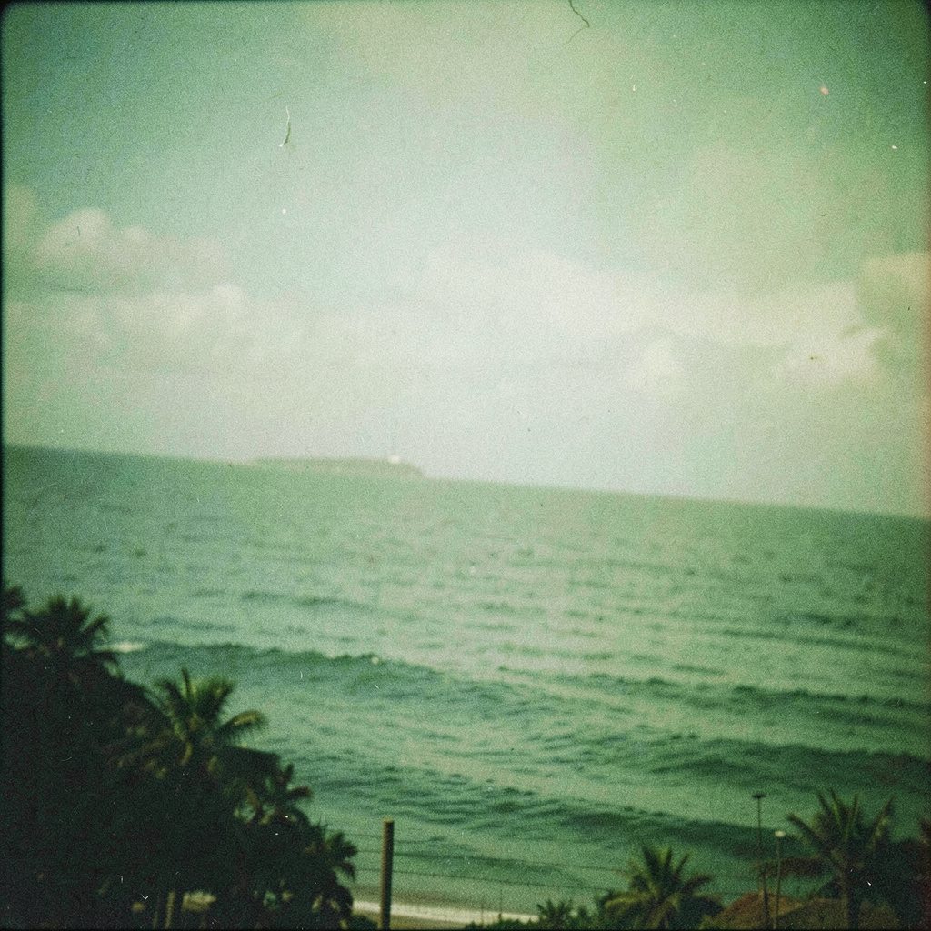 Vista costera de Ponce con cielo gris y mar verde azulado, capturada como una fotografía analógica con grano visible.